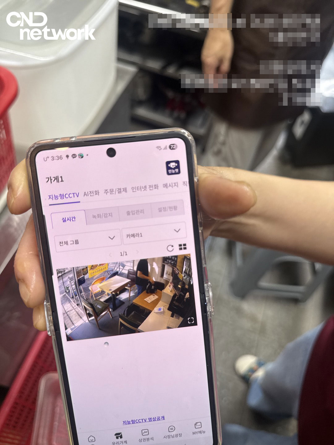 스마트폰 LG U+ 지능형 CCTV 앱으로 매장 실시간 화면을 확인하는 모습